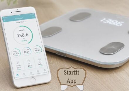 A person stands barefoot on a sleek silver smart weighing scale in a bright, modern bathroom with white tiled floors. Nearby, a white smartphone displays a fitness tracking app featuring colorful teal circular charts for body metrics such as BMI, body fat, and muscle mass. Soft natural light fills the minimalist space, creating a clean and realistic wellness-focused scene.